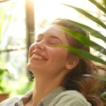 a smiling woman receiving a rejuvenating chiropractic adjustment in a bright, modern office setting, surrounded by vibrant green plants and natural light.